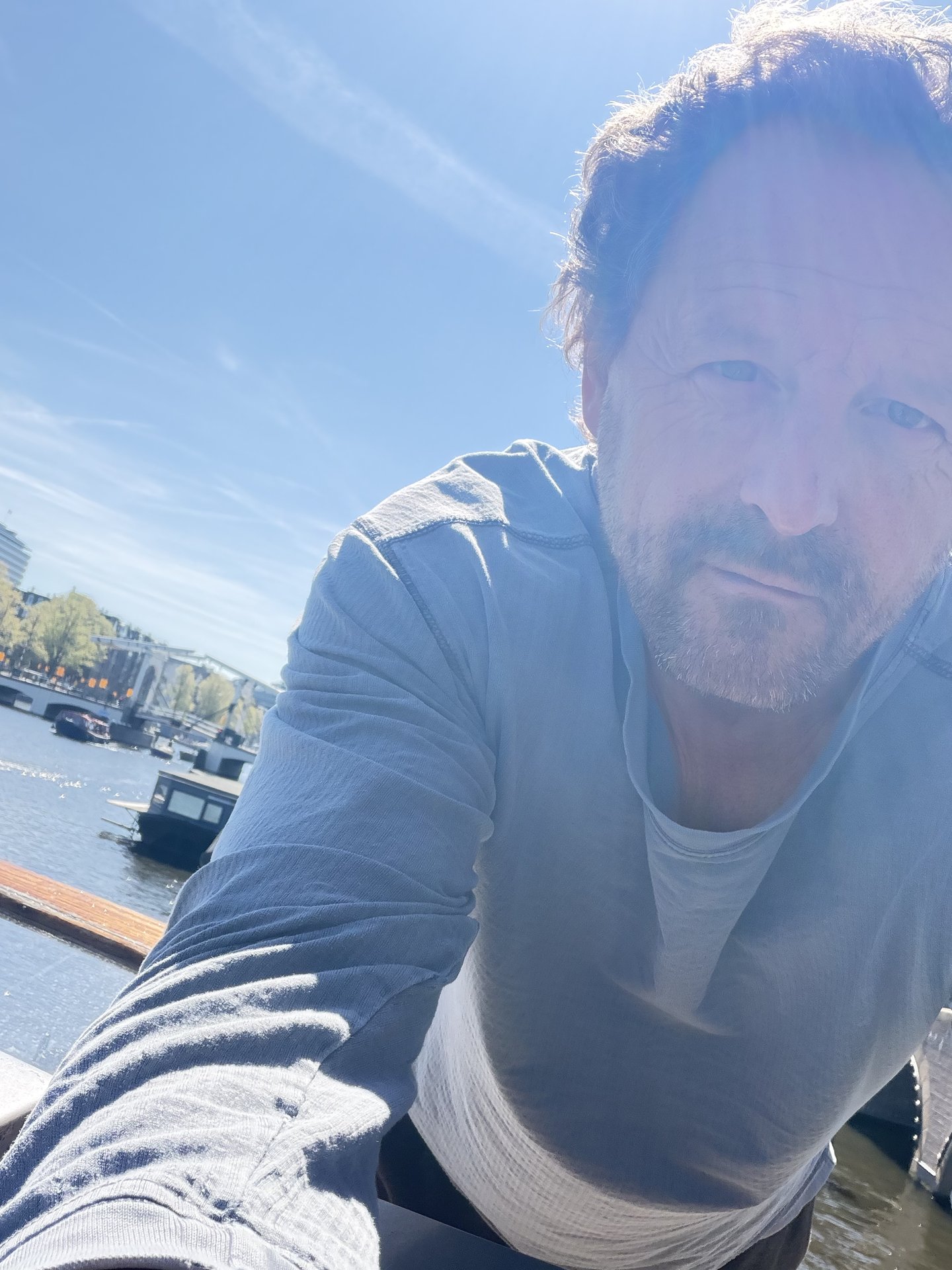 A man takes a sun-drenched selfie, looking directly at the camera with a serious expression